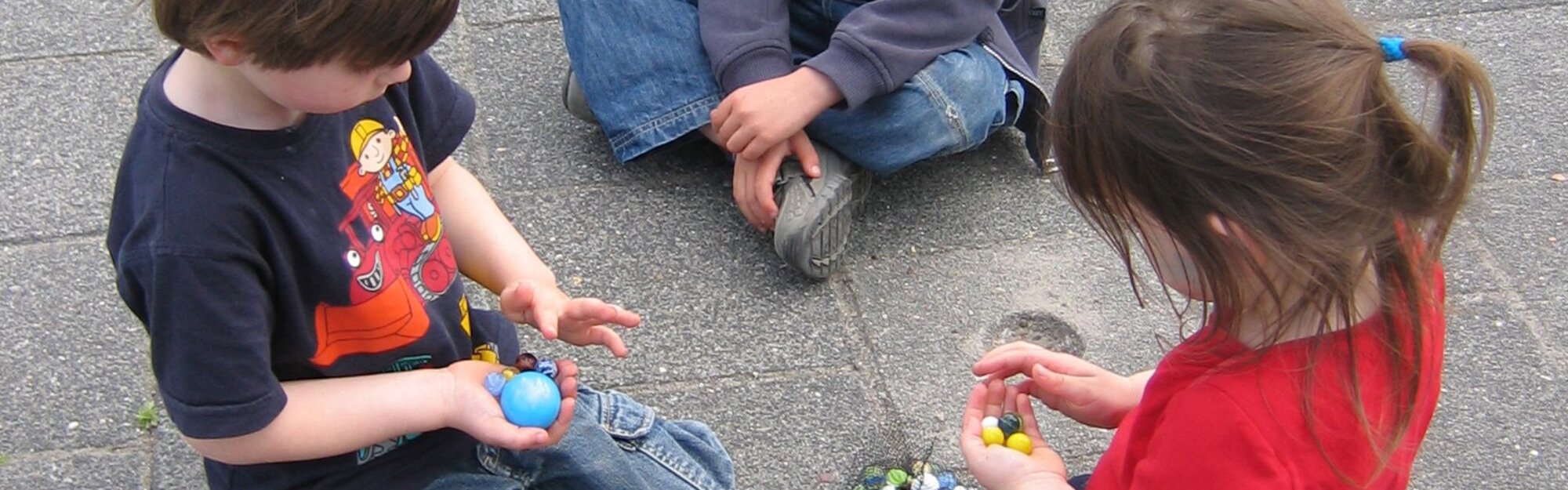 3 børn leger med marmorkugler
