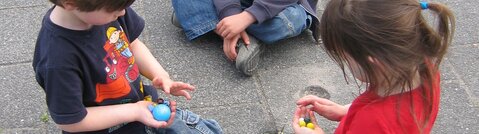 3 børn leger med marmorkugler